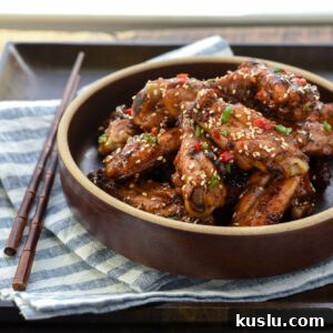Korean honey garlic chicken is garnished with fresh chilies and served in a bowl on a tray.