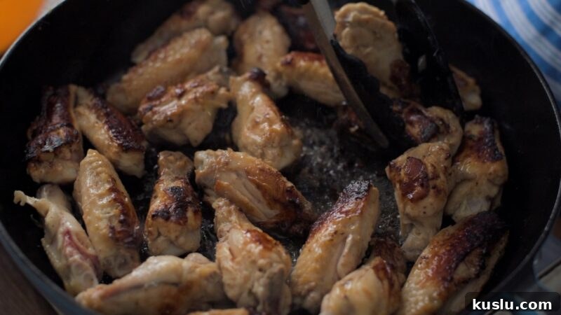 Chicken wings browning in a skillet