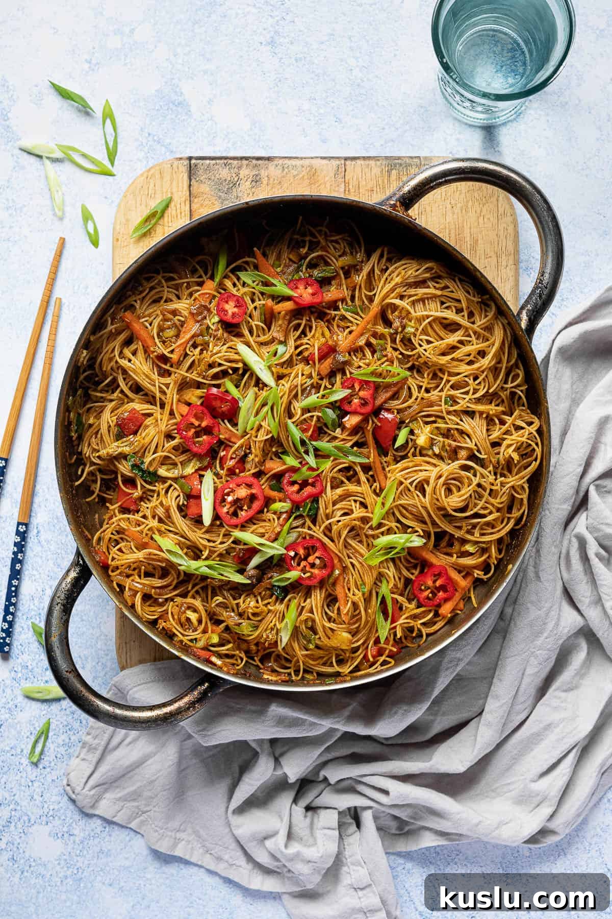 Curry noodles in a pan on a wooden board.