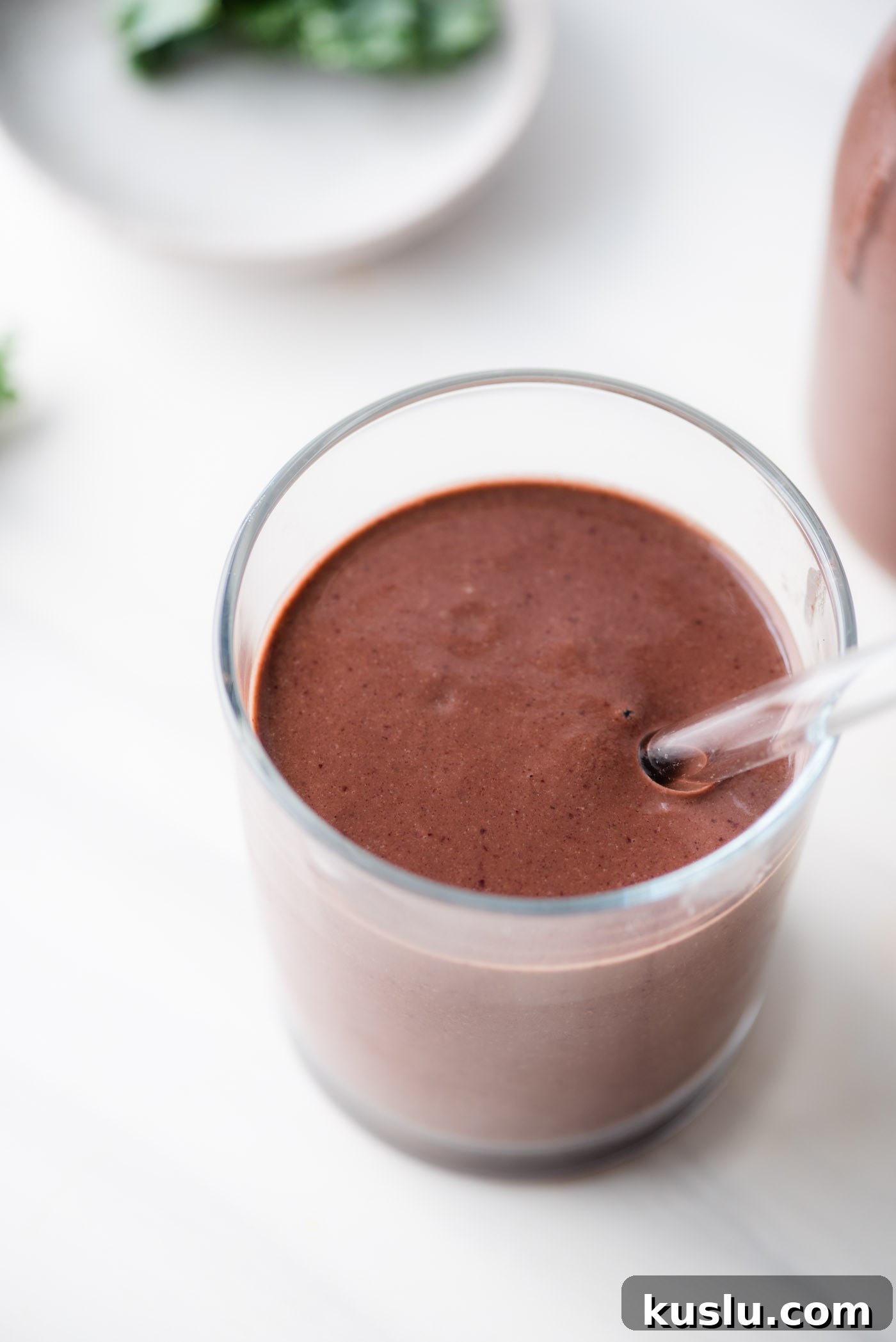 Creamy chocolate cherry smoothie in a glass with a glass straw.