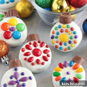 Oreo Cookie Christmas Ornaments on a glittery background with colorful ornaments in a bowl behind them.