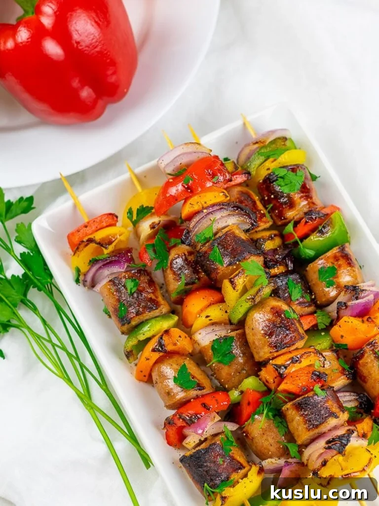 Grilled chicken sausage kabobs on a white plate with red peppers