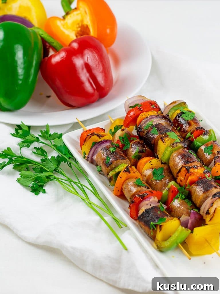 Grilled chicken sausage kabobs on a white plate with red and green peppers