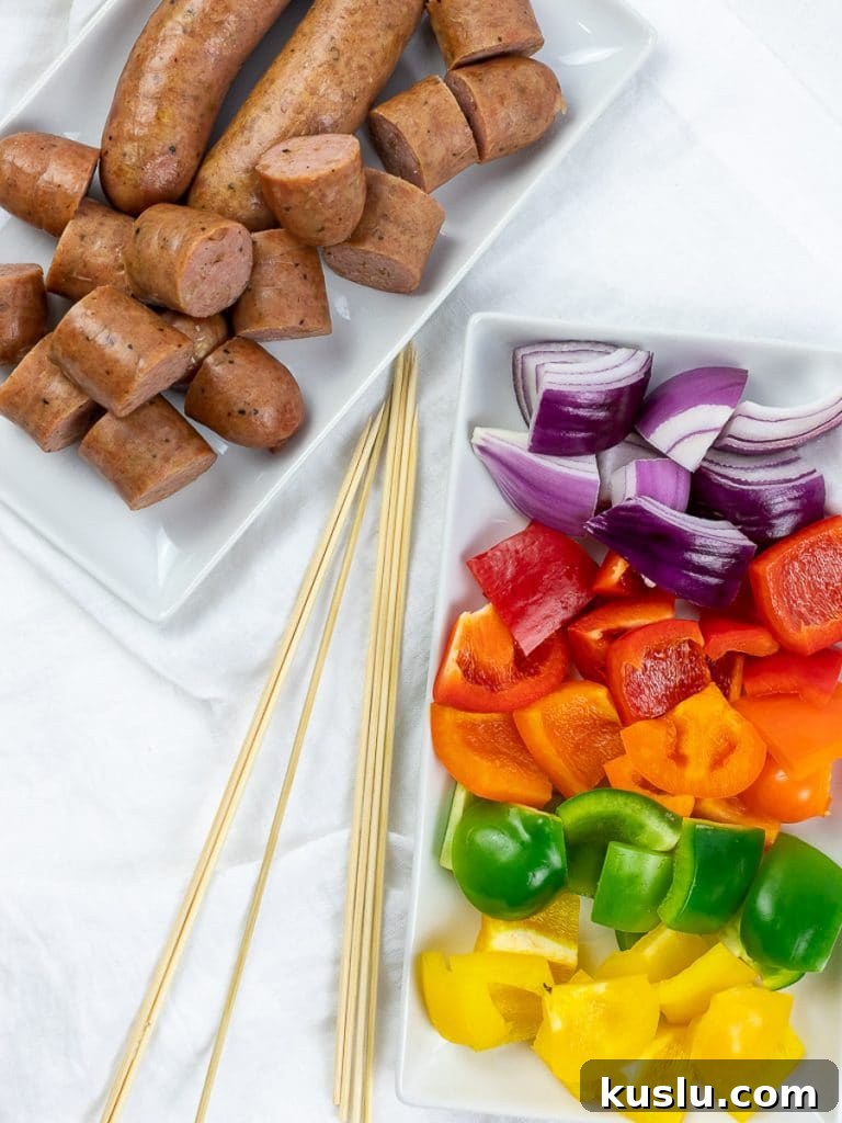 grilled chicken sausage with red, orange, green, yellow peppers, and red onion on a plate next to skewers