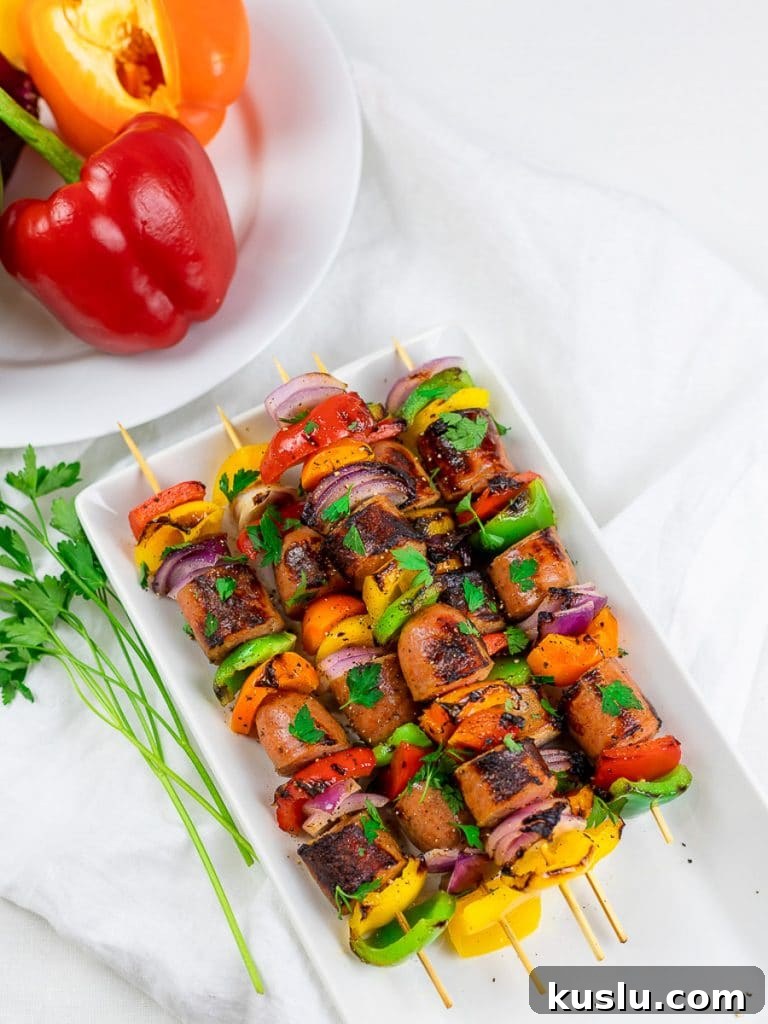 Grilled chicken sausage kabobs on a white plate with red and orange peppers