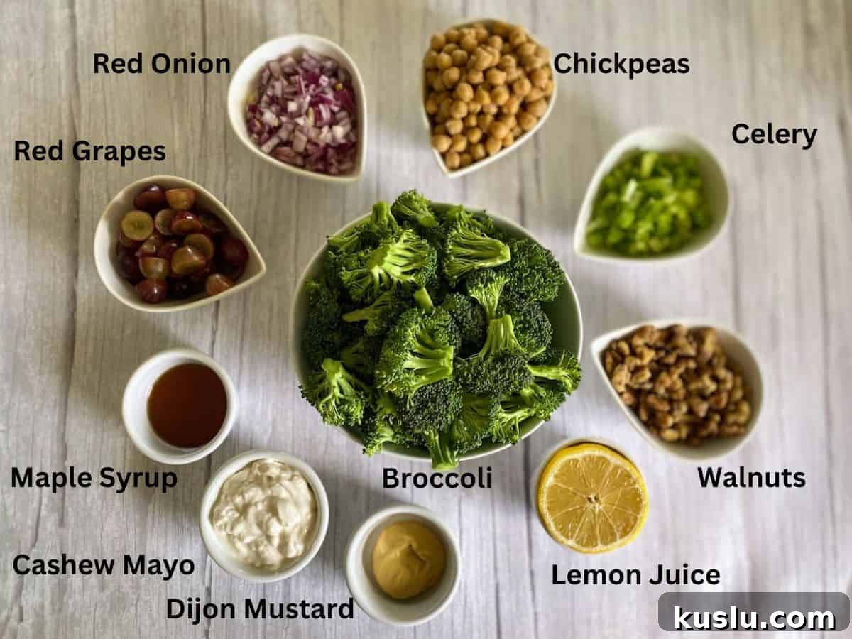 Salad ingredients in bowls on the counter: broccoli, red grapes, red onion, chickpeas, celery, walnuts, lemon juice, dijon mustard, cashew mayo, and maple syrup