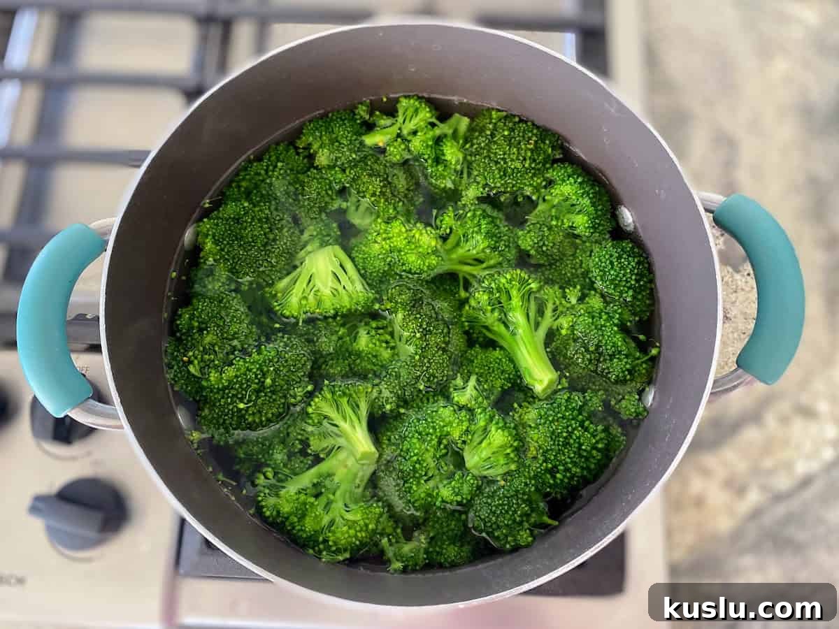 Broccoli is cooking in a pan on the stove.