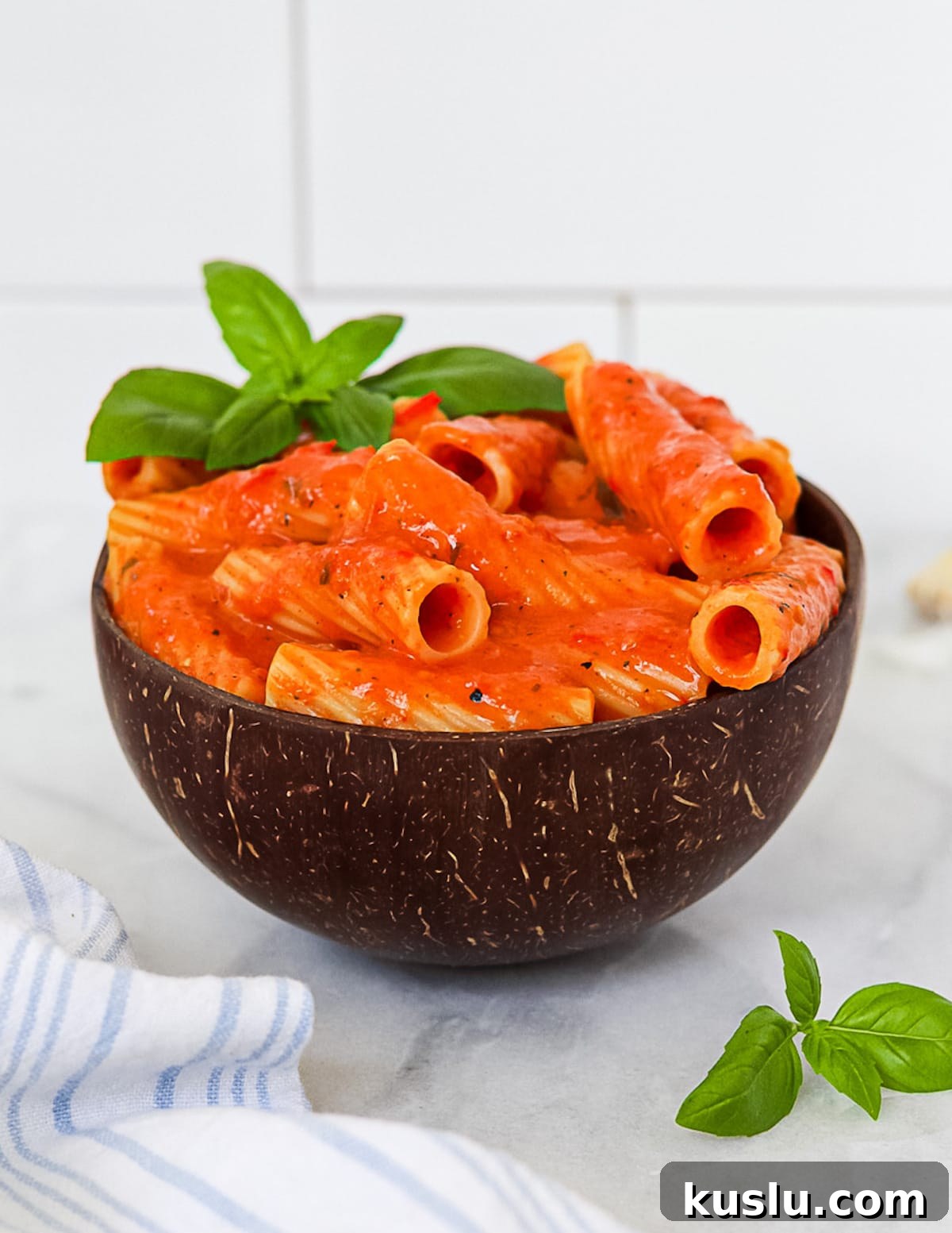 A side angle picture of noodles covered in a red pasta sauce.