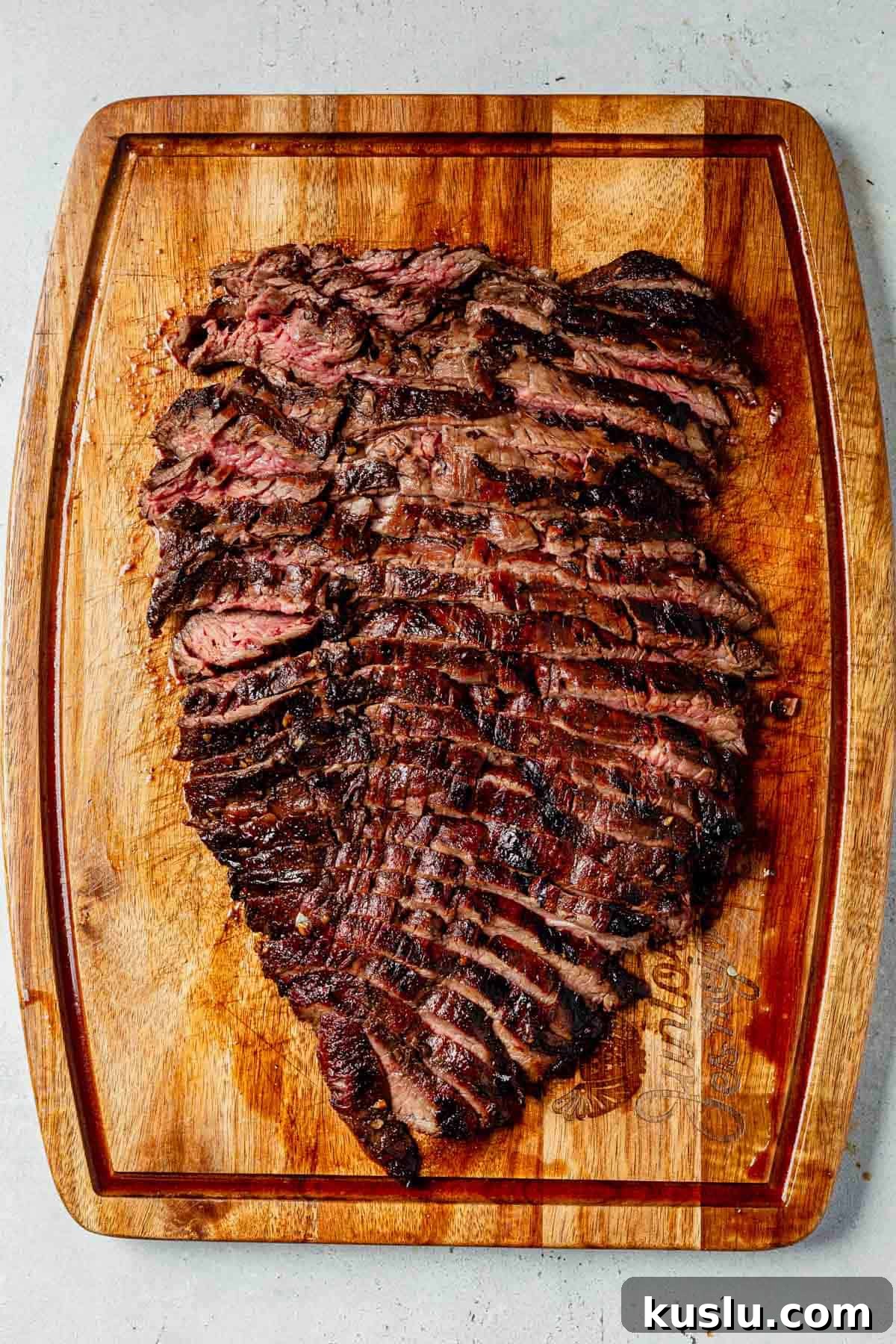 thinly sliced balsamic flank steak on a cutting board
