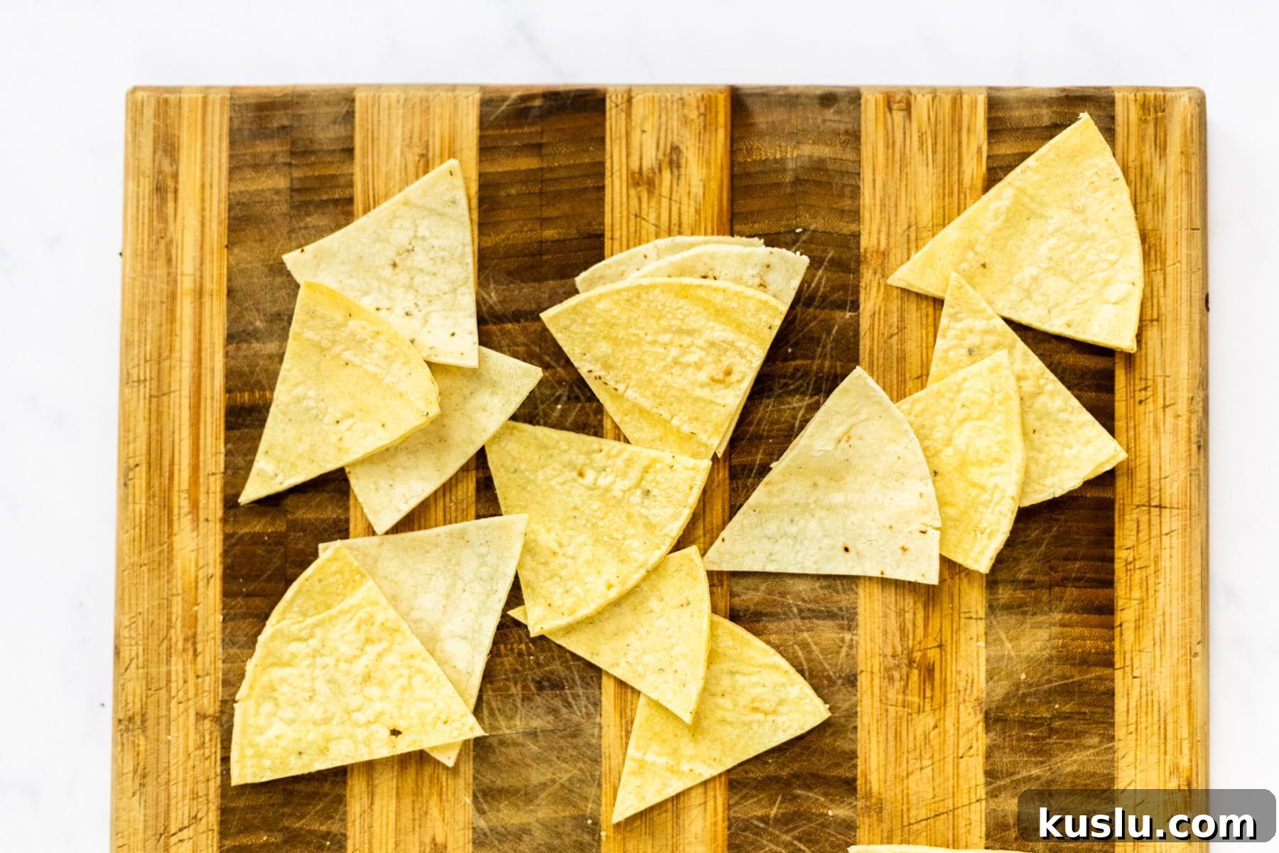 corn tortillas cut into triangles on a cutting board.