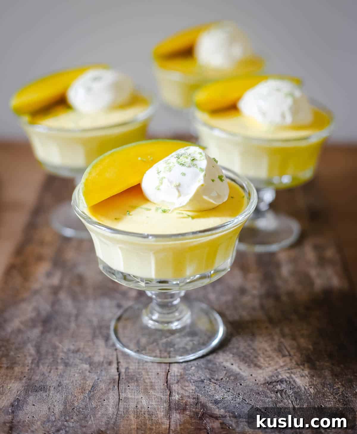 glass bowls of mango pudding on a wooden table