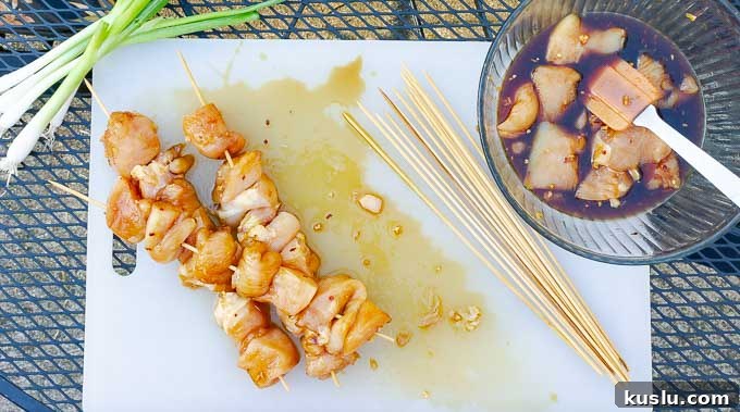 three raw Grilled Asian Chicken Kabobs on a white cutting board