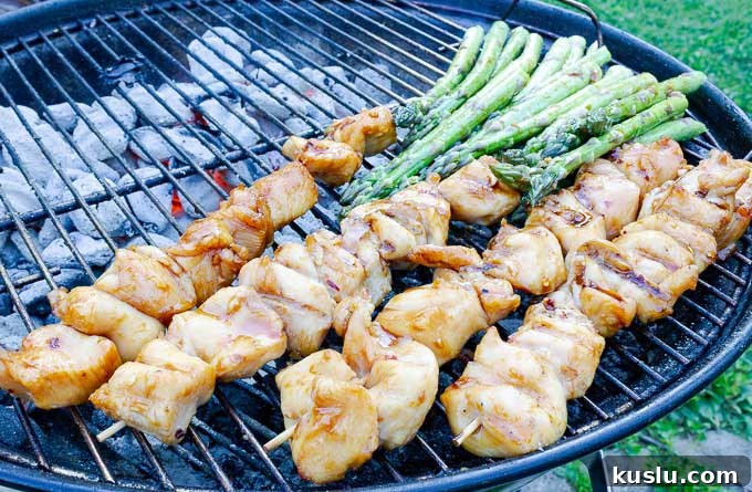 four Grilled Asian Chicken Kabobs on the grill with asparagus