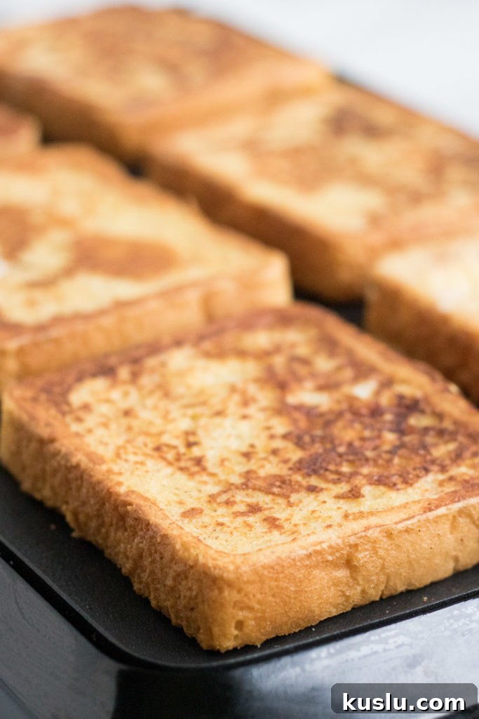 Egg Nog French Toast Recipe- egg nog french toast being cooked on an electric griddle. 