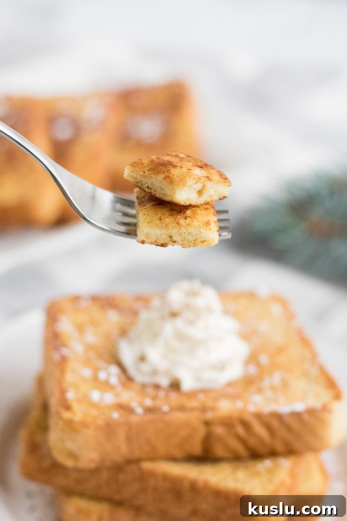 Egg Nog French Toast- a fork with a bite of french toast being held up above the plate. 