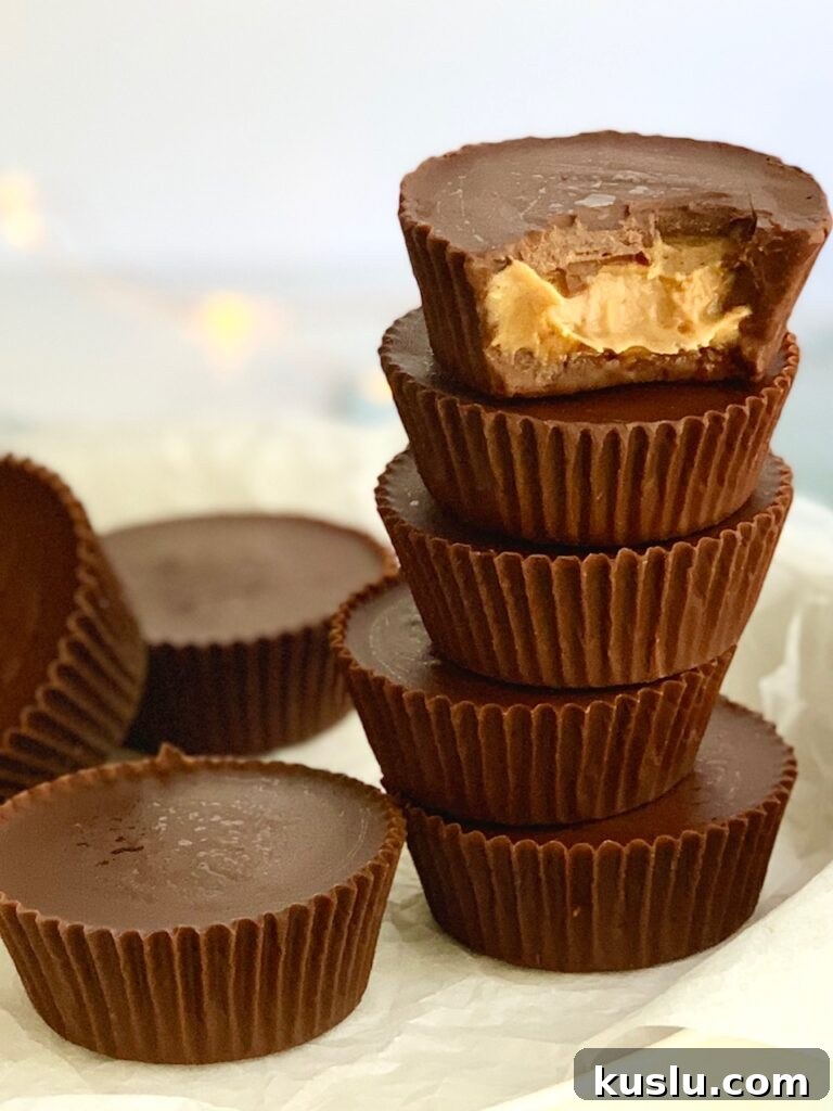 a plate of stacked peanut butter cups and a bite missing out of the top cup. You can see peanut butter. 