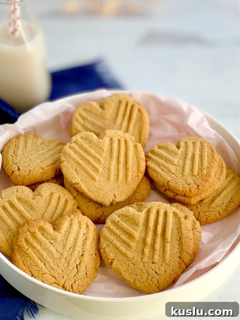Heart-shaped peanut butter cookies with the classic criss cross pattern on them on a platter.