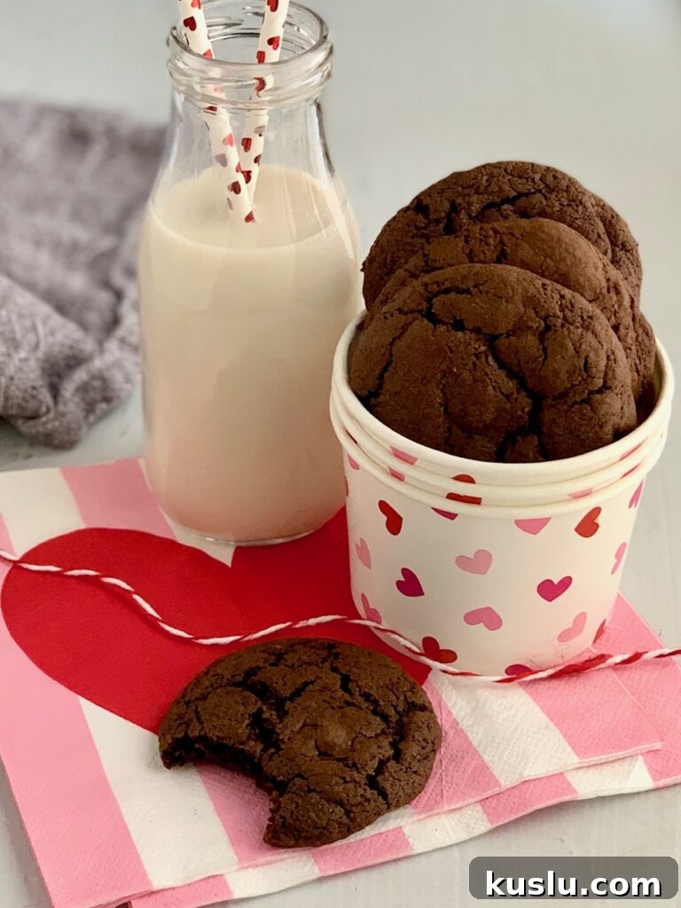 Round brownie cookies with a bite eaten out of one next to a glass of dairy free milk.